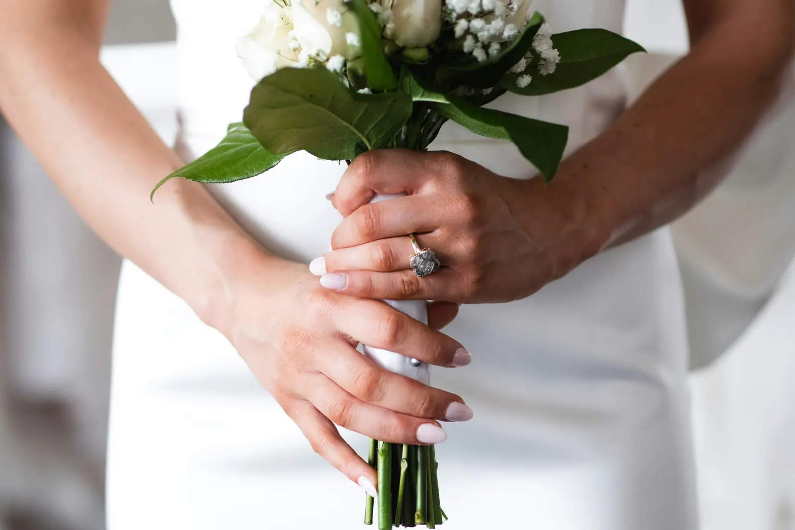 A bride in a simple dress holding a small white bouquet